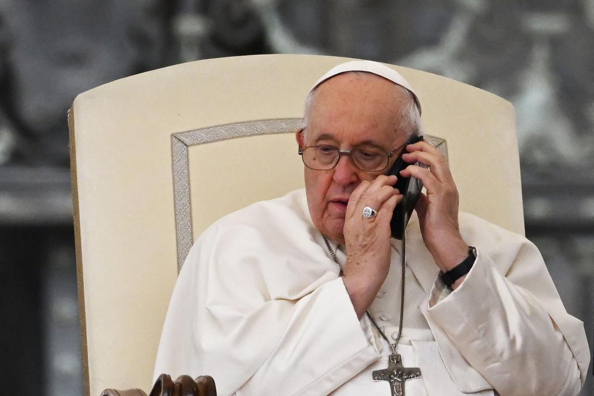 El Papa Francisco habla por teléfono durante la audiencia general semanal en la plaza de San Pedro.