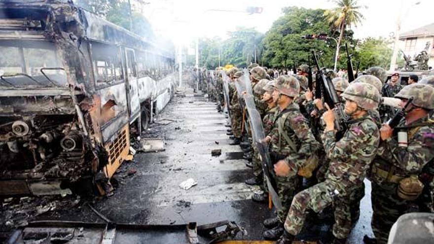 Tropas tailandesas, ante uno de los autobuses quemados por los manifestantes.