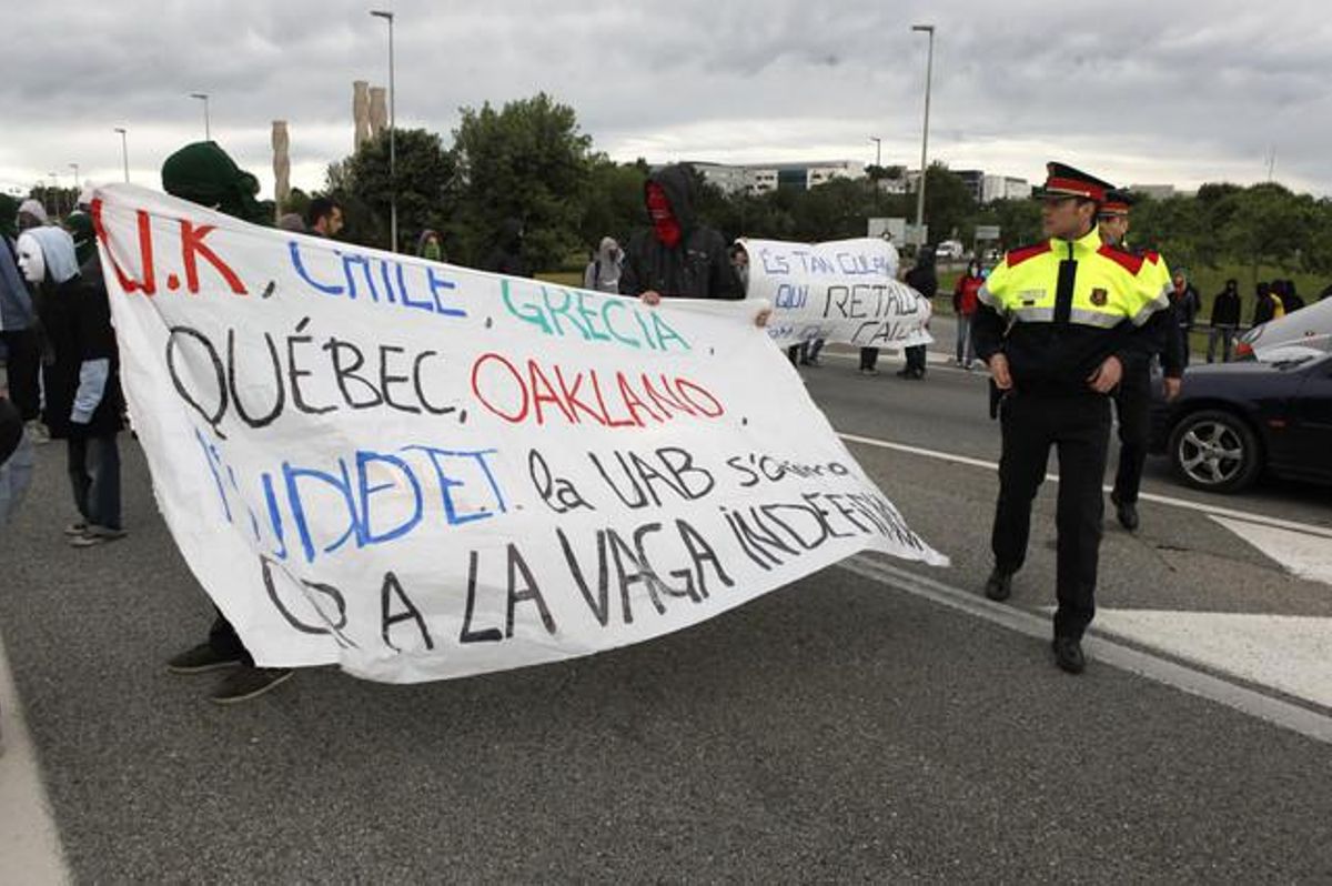 En plena carretera, estudiants de la Universitat Autònoma de Barcelona tallen el trànsit a primera hora del matí amb pancartes contra la precarietat en l’educació pública sota la vigilància dels Mossos d’Esquadra.