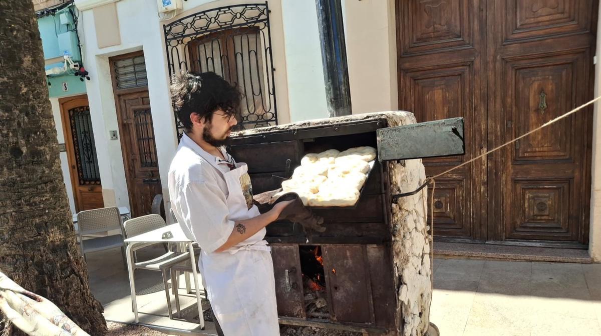Un artesano de Onil saca el pan del horno portátil de leña