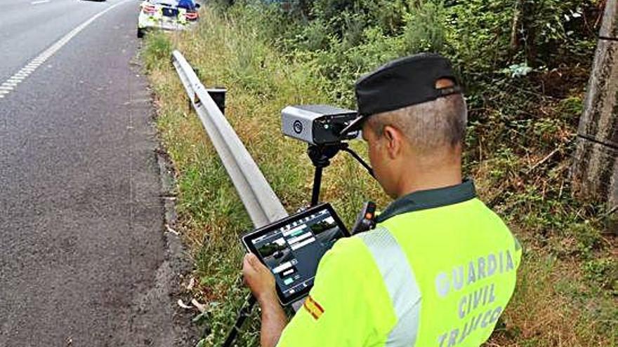 Un agente de la Guardia Civil de Tráfico en una carretera gallega con el lector de matrículas móvil.