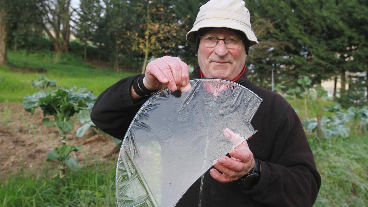 Un hombre, con una placa de hielo que se formó en un cubo con agua de su huerta.