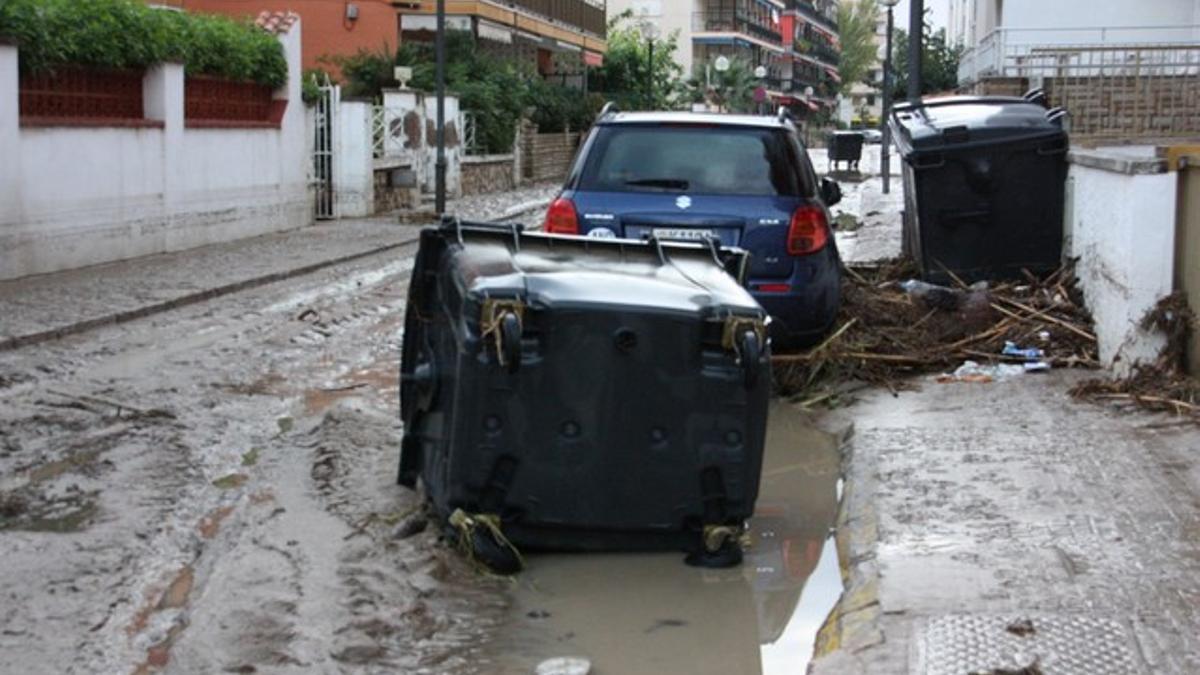 Un contenedor volcado en una calle de Salou, afectada por las intensas lluvias, este lunes.