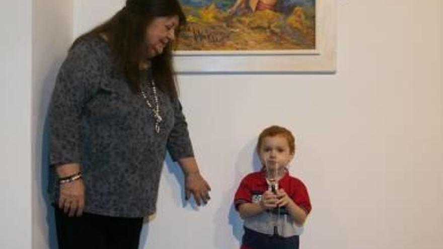 La artista con su prima, Asunción Valdés. Abajo, con el niño protagonista del cuadro y durante la inauguración.