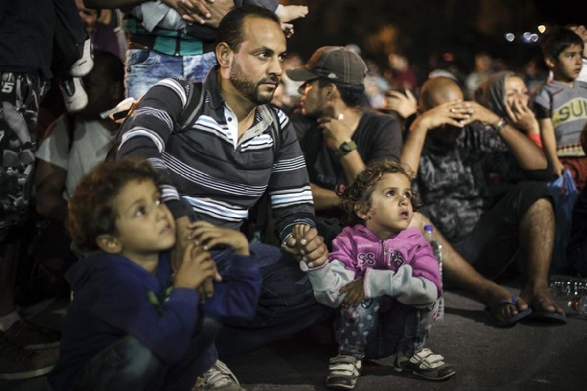Un padre sirio y sus hijos espera para subir al ferry en la isla griega de Lesbos.