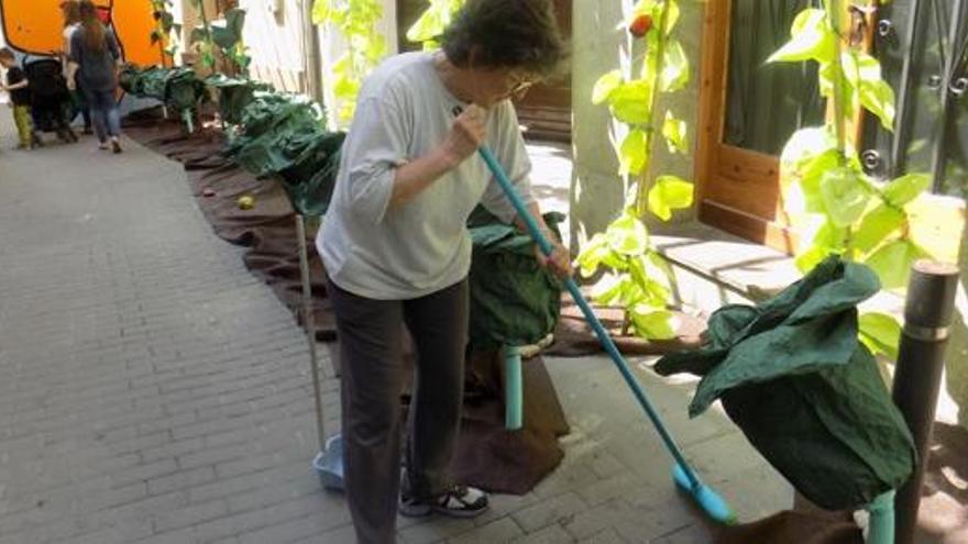 Una veïna passant l&#039;escombra entre les decoracions del carrer Sant Bernat