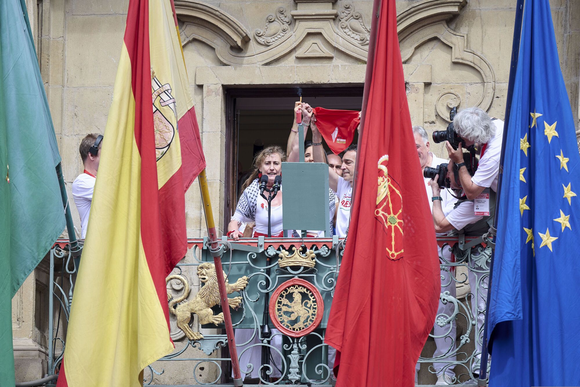 Los tres representantes de Yala Nafarroa por Palestina Dyna Kharrat (c), Lidón Soriano (i) y Eduardo Ibero realizan el Chupinazo con el que comienzan los Sanfermines desde el balcón del ayuntamiento de Pamplona, este domingo. EFE/ Daniel Fernández. amplía info y añade fotos