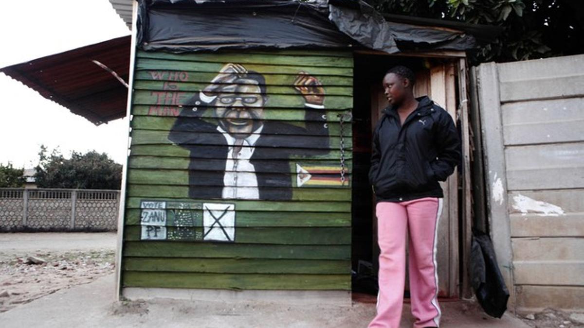 Una joven pasa ante un mural de Mugabe en Harare.