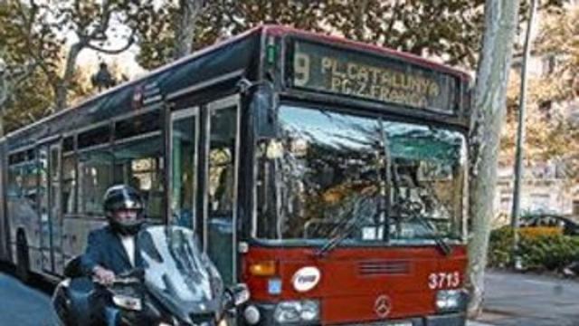 Un bus adelanta a una moto que circula por el carril bus de la Gran Via.