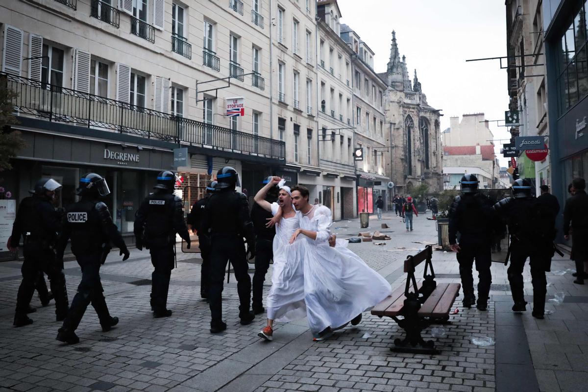 Los disturbios se extienden por Francia en la cuarta noche de protestas. La policía antidisturbios francesa pasa junto a hombres disfrazados durante una manifestación en Caen, noroeste de Francia