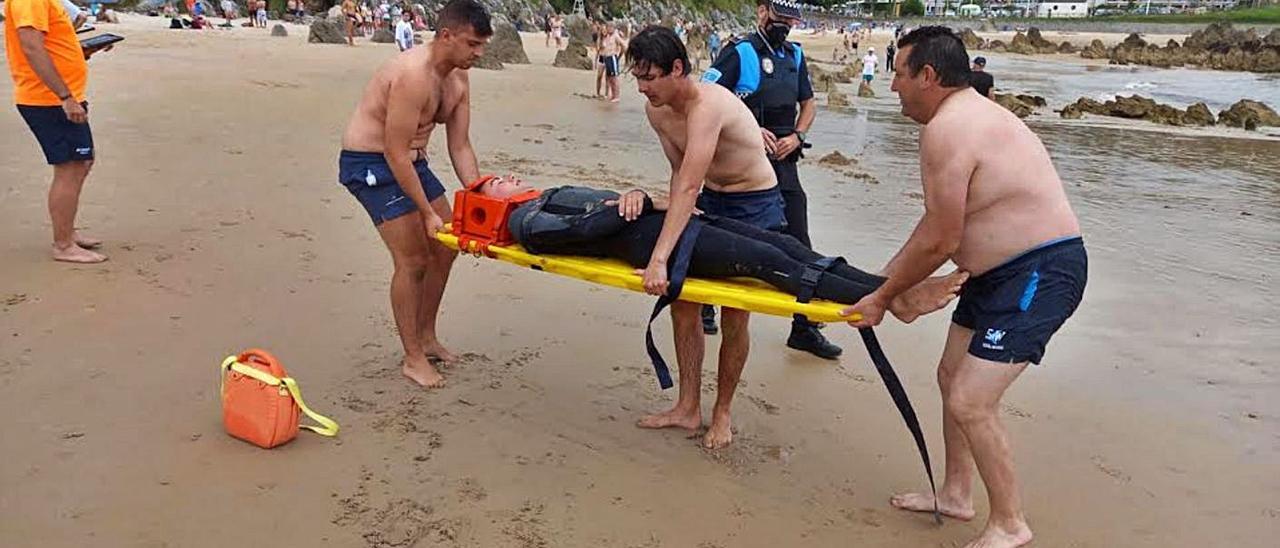 Los socorristas, la Policía Local y un bañista, trasladando a la “víctima” hasta la ambulancia. | María Villoria
