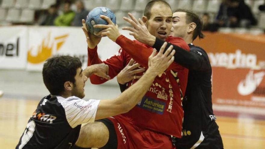 Adrián Fernández intenta lanzar presionado por dos jugadores de La Roca.