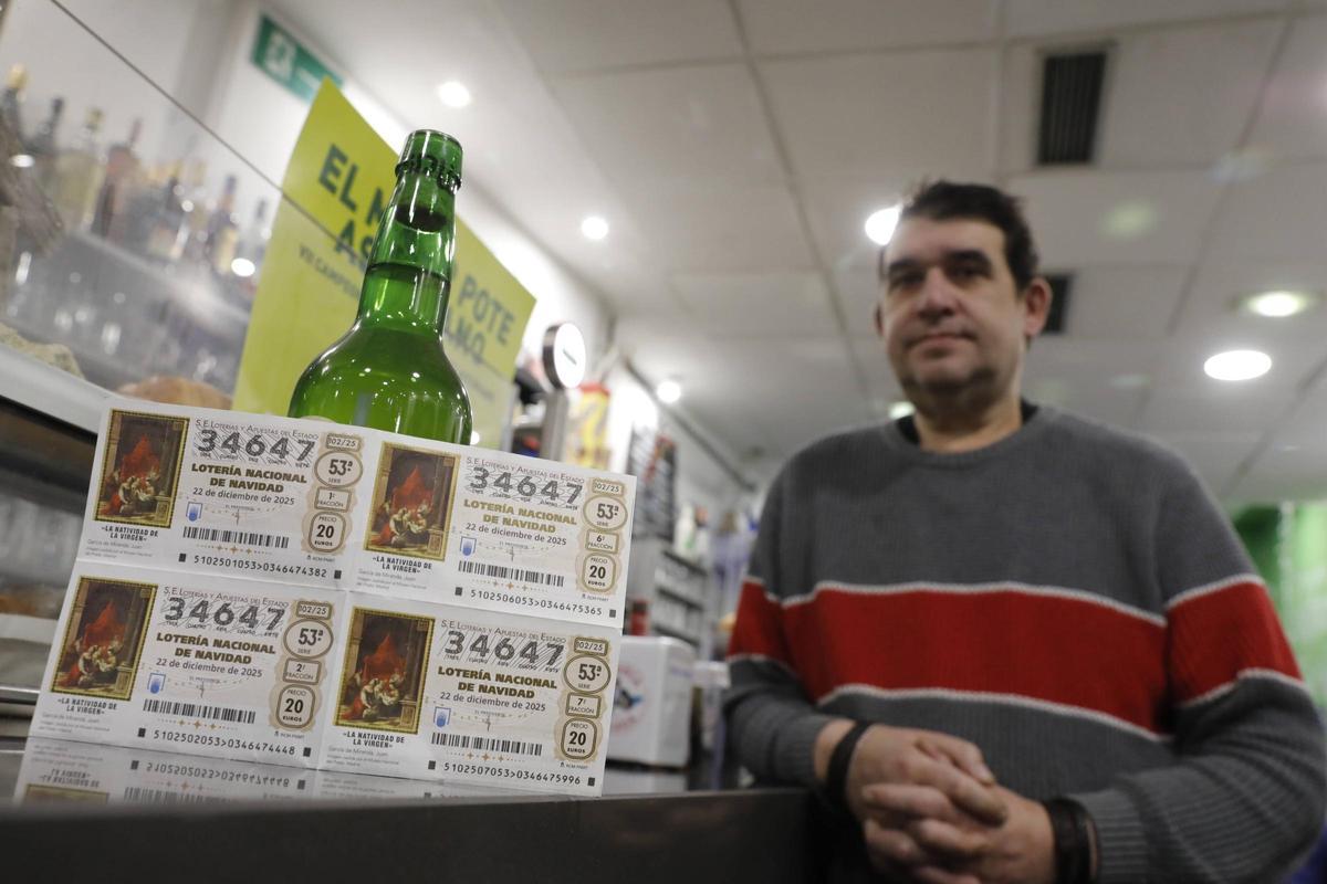 Javier Suárez, con décimos y una botella de sidra en su restaurante de Oviedo