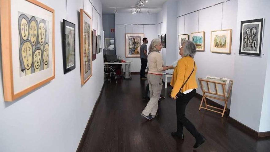 Varios visitantes observan las obras de la exposición de Celestino Poza en el local de Arga.