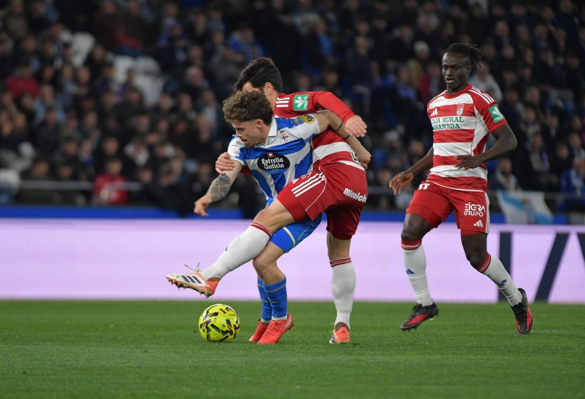 Mario Soriano protege el balón ante dos jugadores del Granada.