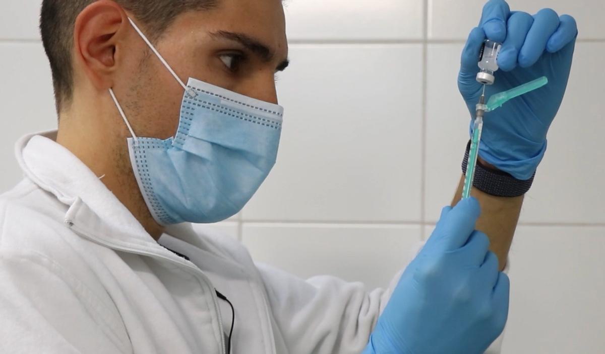 Un sanitario prepara una vacuna.