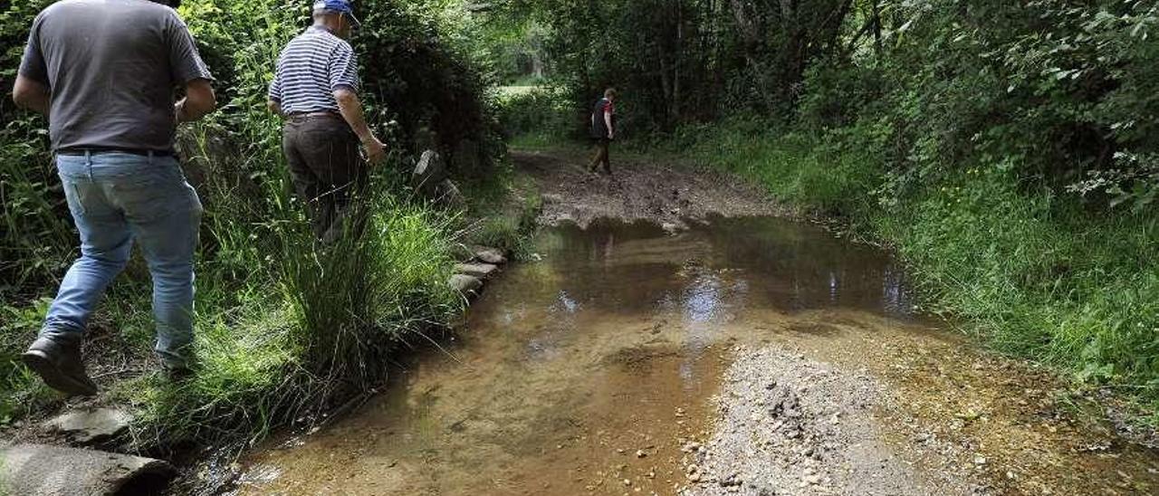 Tres vecinos muestran el estado de uno de los caminos de la aldea. // Bernabé/Javier Lalín