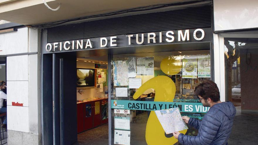 Un joven consulta un plano frente a la Oficina de Turismo.