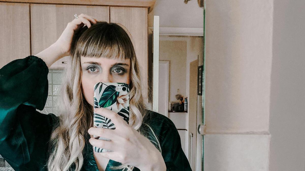 Una joven se saca un selfi con la ayuda de un espejo.