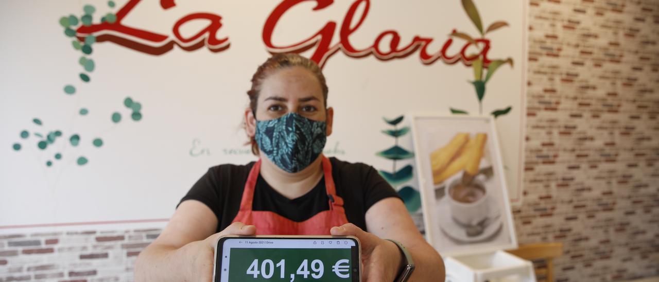 Georgina Olivar muestra en su móvil el importe del ultimo recibo de la luz en su negocio de Gijón