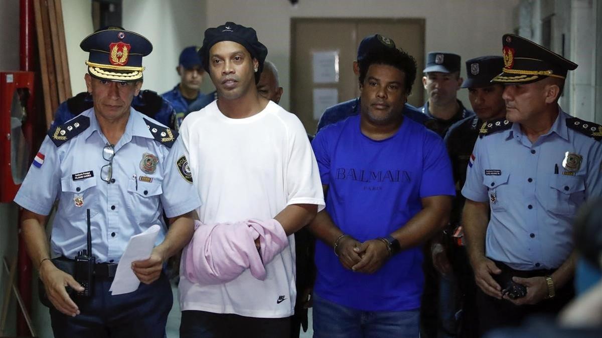 Ronaldinho y su hermano Roberto, esposados y conducidos por la policía a declarar en los juzgados de Asunción.