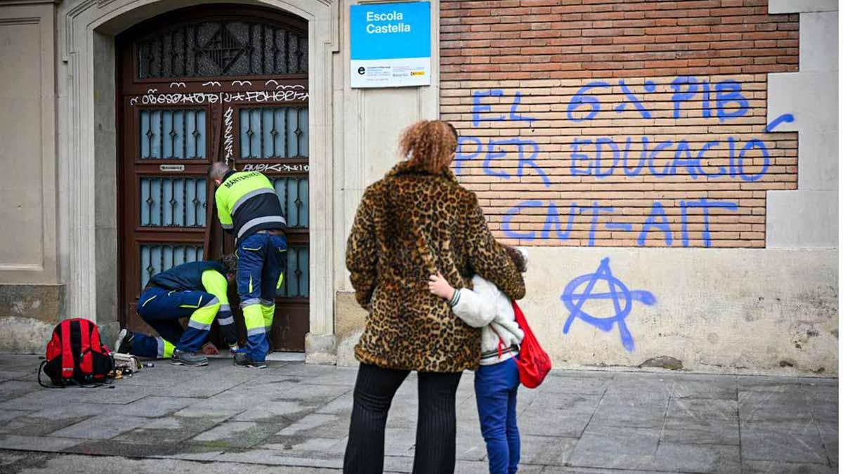 Unos técnicos tratan de abrir la puerta de la escuela Castella, en el Raval, que ha sido sellada con silicona, en el primer día de huelga de maestros