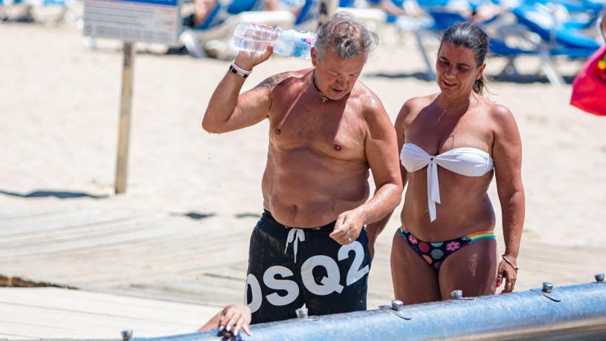 Bañistas refrescándose en una batería de lavapiés en la playa de Levante de Benidorm