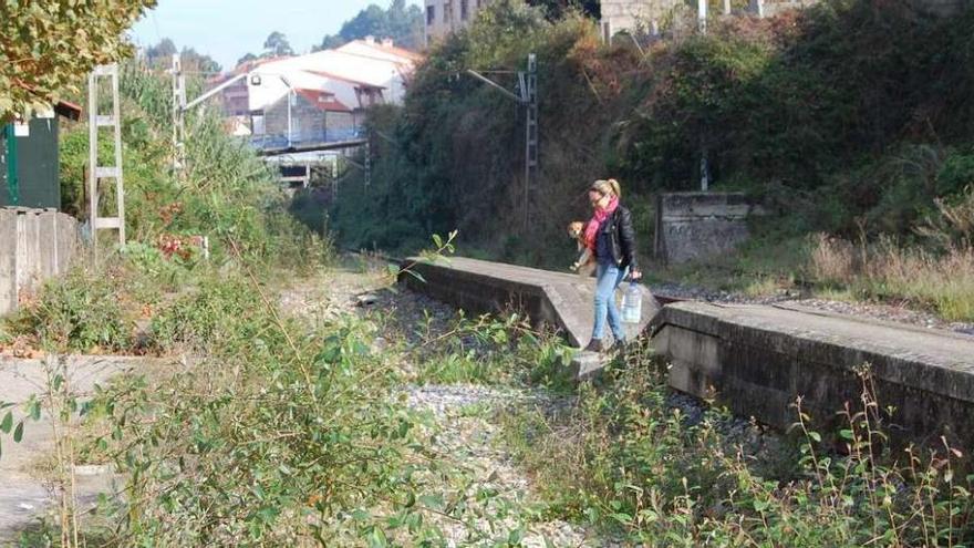 Una persona atraviesa las vías del ferrocarril en Chapela, llenas de maleza. // Faro