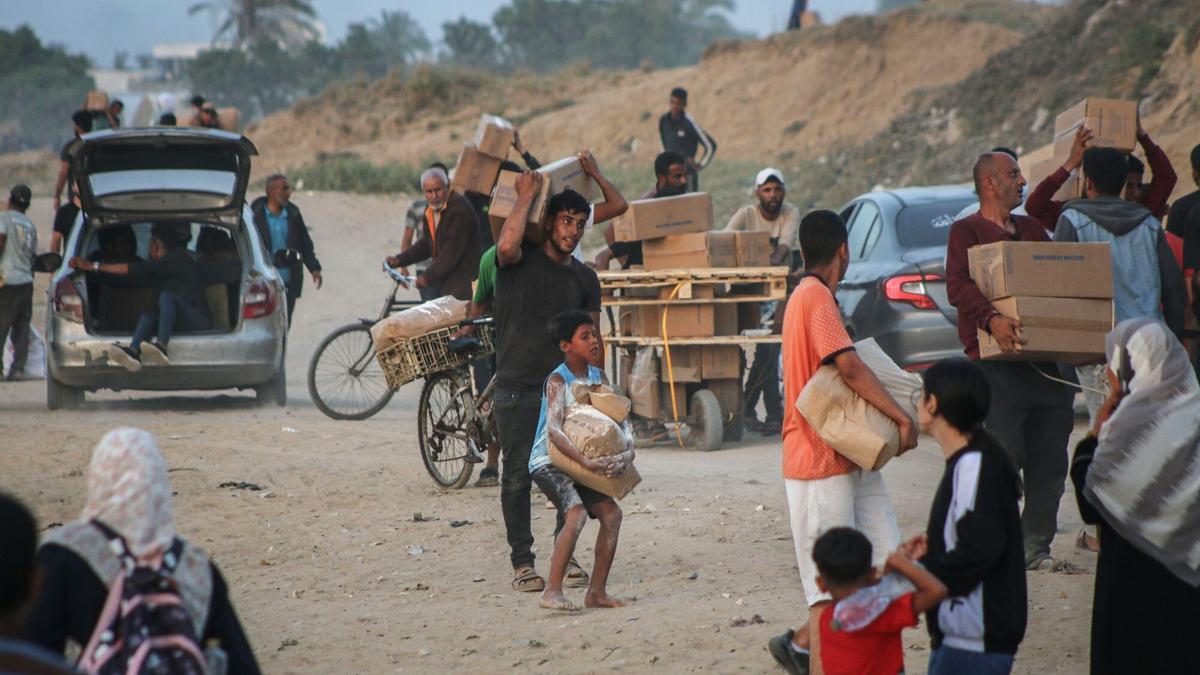 Los palestinos desplazados recogen la ayuda alimentaria que entró en el sur de la Franja de Gaza a través del Programa Mundial de Alimentos de las Naciones Unidas en la zona de Wadi Gaza, en el centro de Gaza.