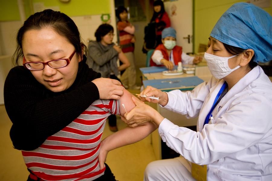 Una sanitaria inyecta a una vacuna a una mujer en China.