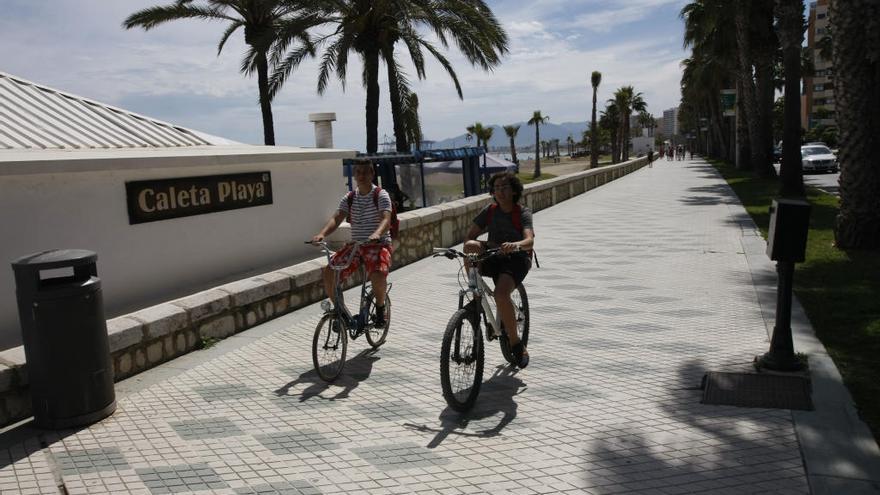 Dos personas pasean en bicicleta por el paseo marítimo.