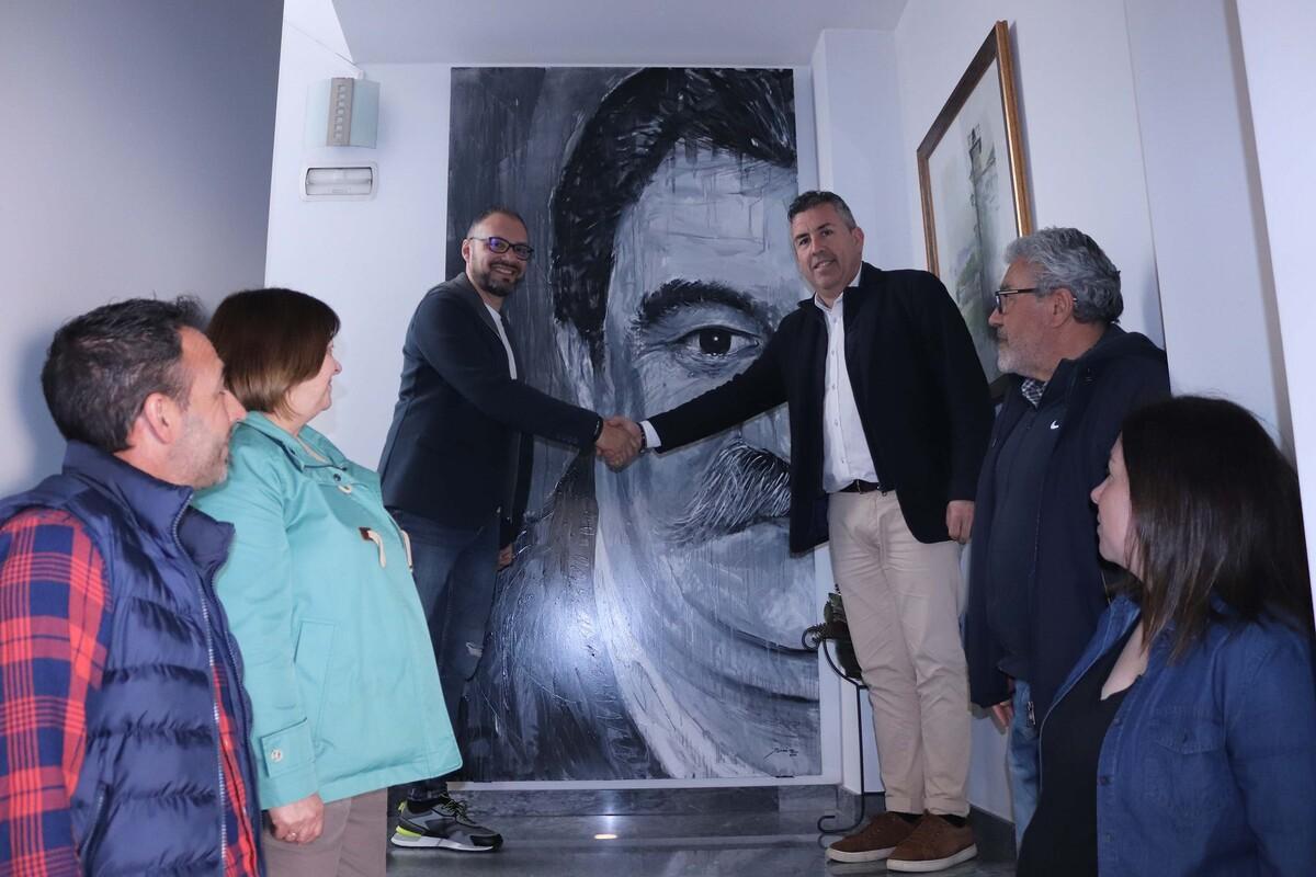 Yáñez estrecha la mano del alcalde de Brión, Pablo LAgo, con el retrato de Vizoso detrás