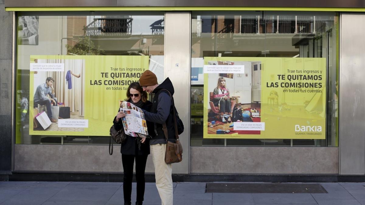 Tourists look at a city map in front of a Bankia bank branch in the Andalusian capital of Seville