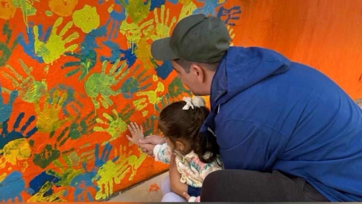 Una niña participa en un mural colaborativo en el barrio Orba para conmemorar el aniversario de la dana.