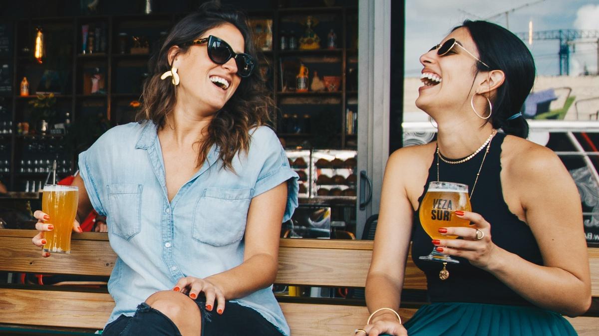 Dos amigas se ríen tomando unas cervezas