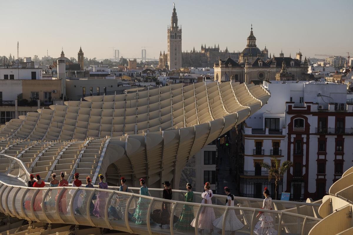 óvenes vestidas con trajes de flamenca de varios diseñadores desfilan este lunes por el mirador de Las Setas de Sevilla durante la presentación de la Semana Internacional de la Moda Flamenca (SIMOF) en su edición de 2026