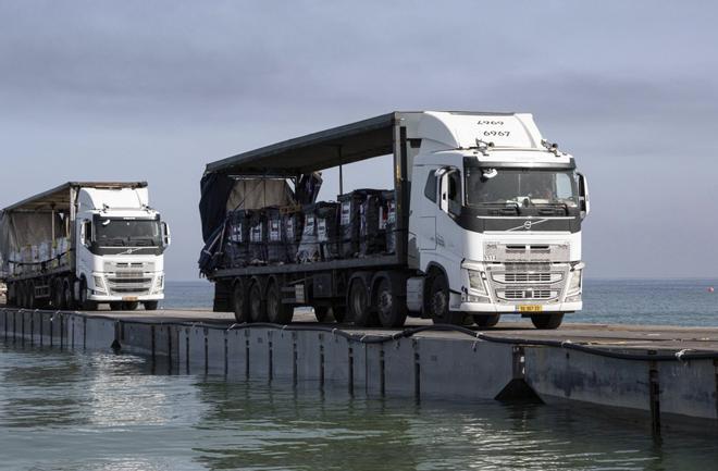 Camiones cargados con ayuda humanitaria cruzan el muelle flotante hacia la Franja de Gaza