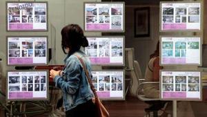 Una joven pasa por delante de una oficina de venta de pisos