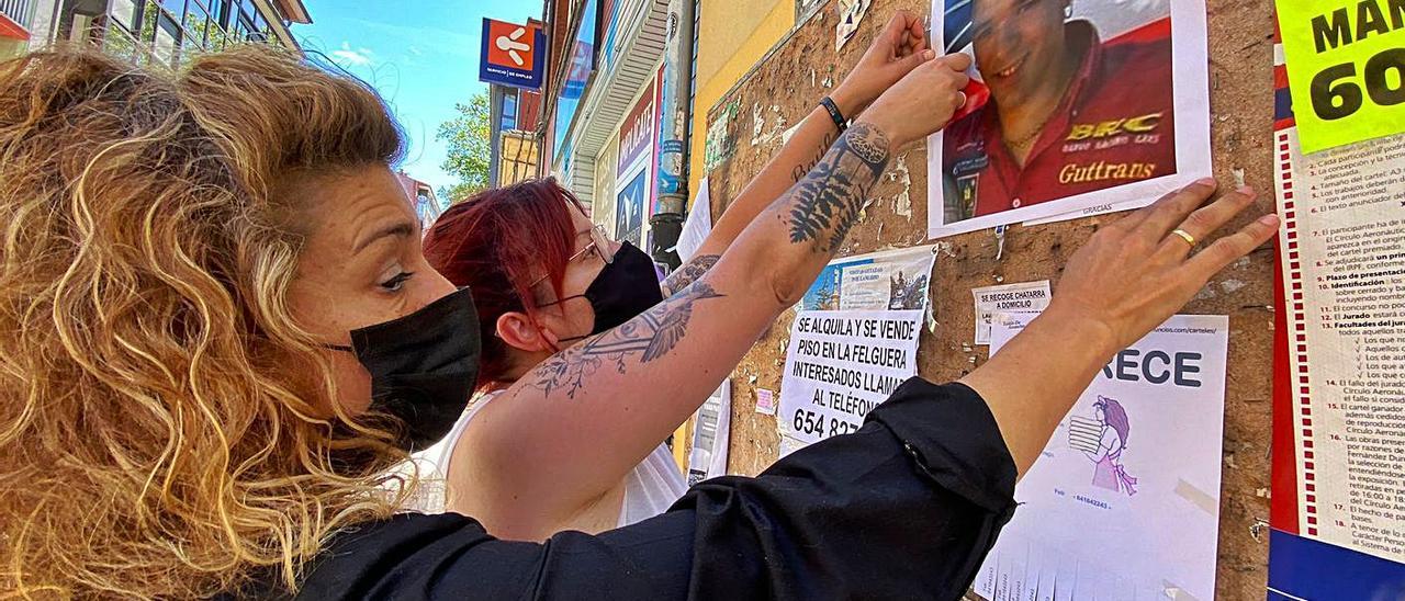 Puri Castro, en primer término, junto a Dubi Lapa, pegan uno de los carteles impresos con la imagen de Iván Castro, pidiendo justicia . | C. M. B.