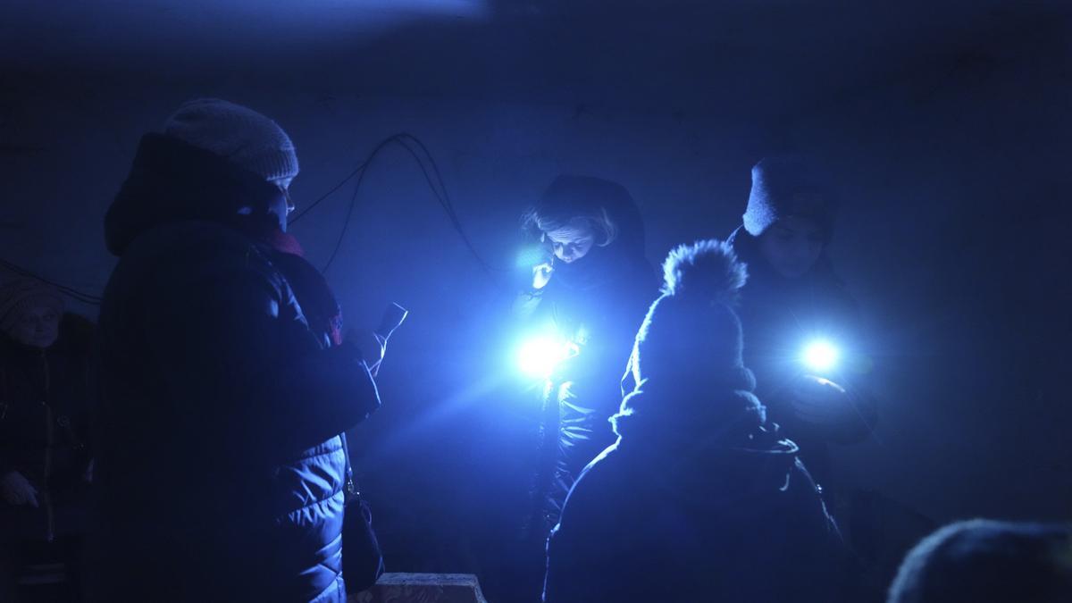 Ukraine, Mariupol: Eine Frau spricht am Telefon und befindet sich mit anderen Menschen in einem Schutzraum während des russischen Beschusses in Mariupol.