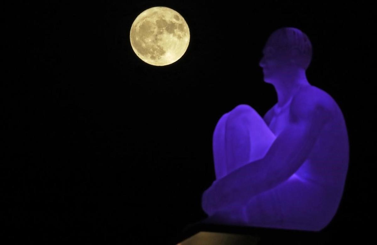 La superluna detrás de una de las siete estatuas del artista español Jaume Plensa en la plaza de Massena en Niza, Francia.