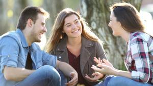 Tres amigas felices hablando sentado en el césped en un parque