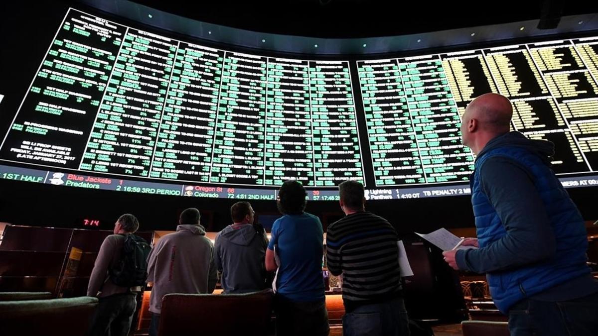 Usuarios de una casa de apuestas de Las Vegas observan el panel de opciones disponible para un partido de fútbol americano entre los Atlanta Falcons y los New England Patriots.