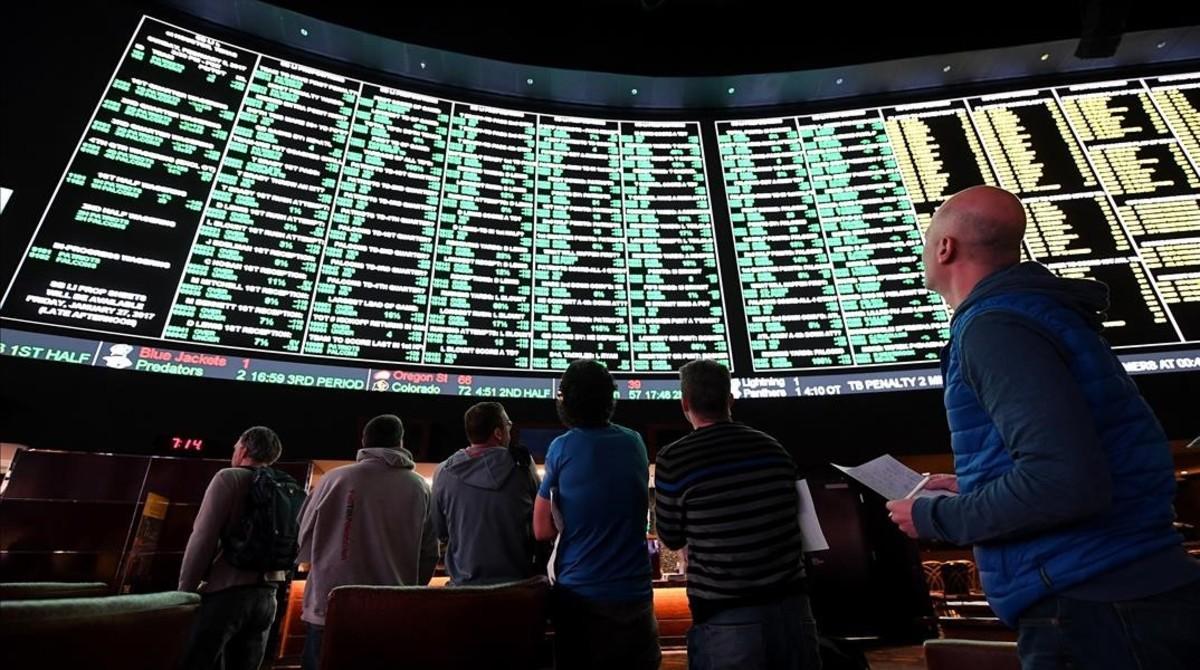 Usuarios de una casa de apuestas de Las Vegas observan el panel de opciones disponible para un partido de fútbol americano entre los Atlanta Falcons y los New England Patriots. 