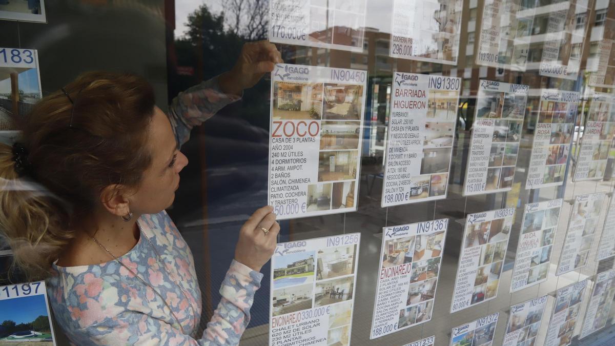 Una mujer coloca anuncios de pisos en el escaparate de su inmobiliaria en Córdoba.