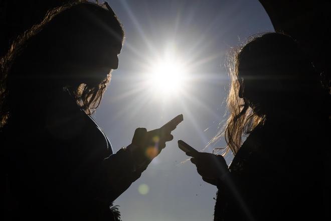 Dos adolescentes, con sus móviles.