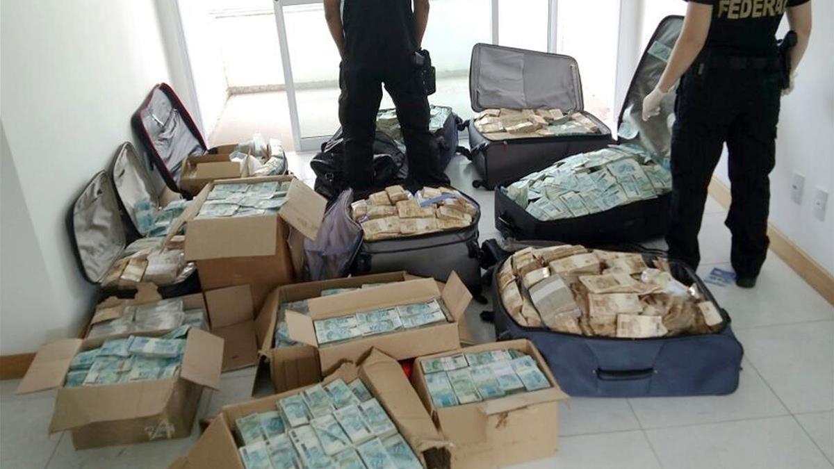 Maletas y cajas con enormes fajos de billetes de la divisa brasileña, en el piso registrado por la policía, en Salvador de Bahía, el 5 de septiembre.