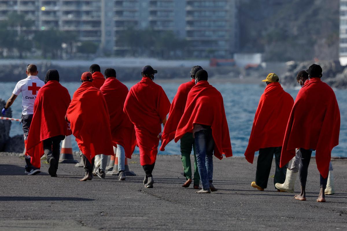 Los migrantes rescatados esta tarde caminan por el muelle de Arguineguín.