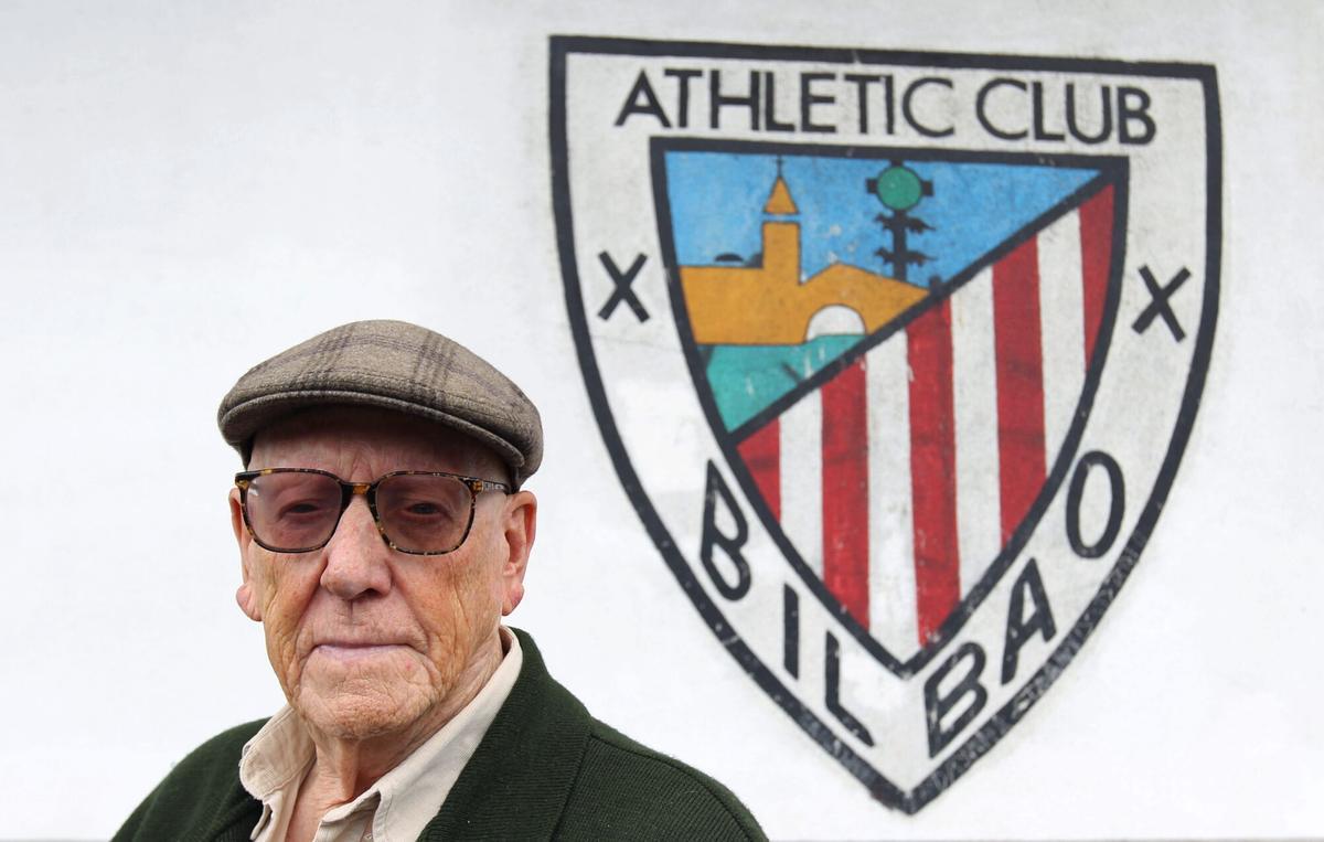 El escritor Ramiro Pinilla posa en la sala de prensa del estadio de San Mamés, ante el escudo del club, en una imagen de 2012