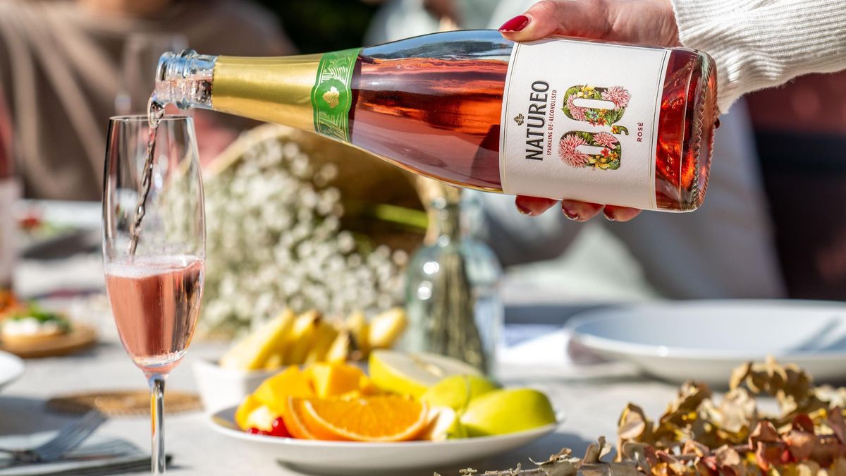 Una mujer sirve una copa de Natureo Rosé, un vino desalcoholizado de Família Torres.